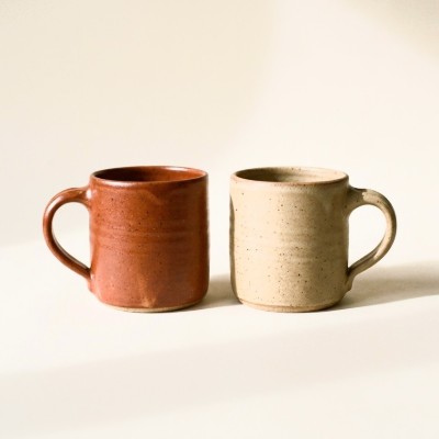 A pair of stoneware mugs, one terracotta and one sand.